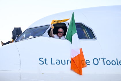 Aer Lingus pilot waves from cockpit window beside Irish flag on aircraft St Laurence O’Toole, symbolising Aer Lingus pilots during ongoing Aer Lingus industrial relations and pilot dispute.