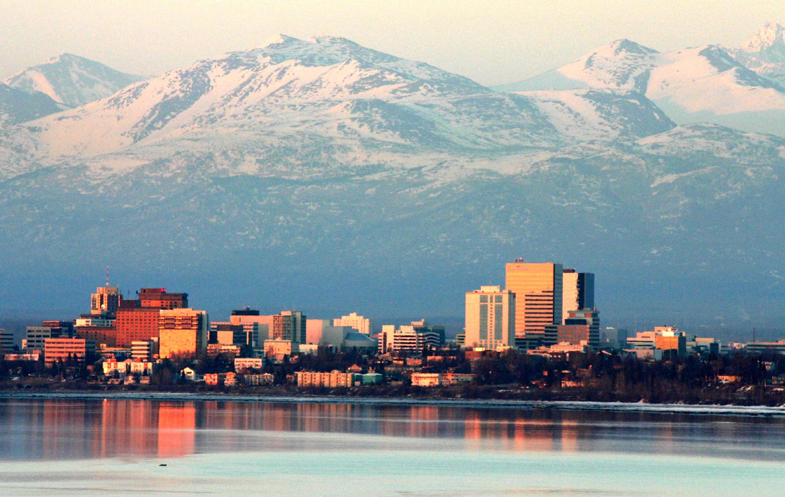 The Anchorage skyline with mountains in the background and water in the foreground.