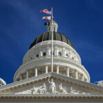 Close-up view of the California State Capitol dome with the U.S. and California flags flying above, symbolising government decisions affecting the U.S. government shutdown and national aviation crisis.