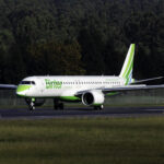 A white aircraft with green text, reading "Binter", is touching down on the runway.