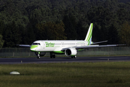 A white aircraft with green text, reading "Binter", is touching down on the runway.