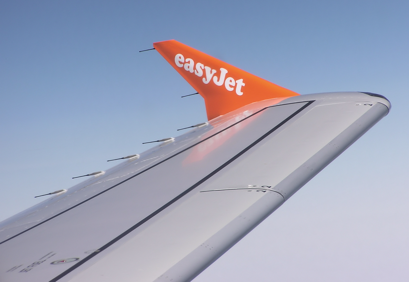 The wing of an easyJet aircraft in the air.