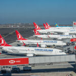 A fleet of Istanbul Airlines planes with red tail and crane logo wait to take off.
