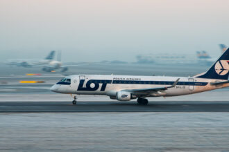 A LOT Polish Airlines aircraft coming in for landing on a snowy runway.