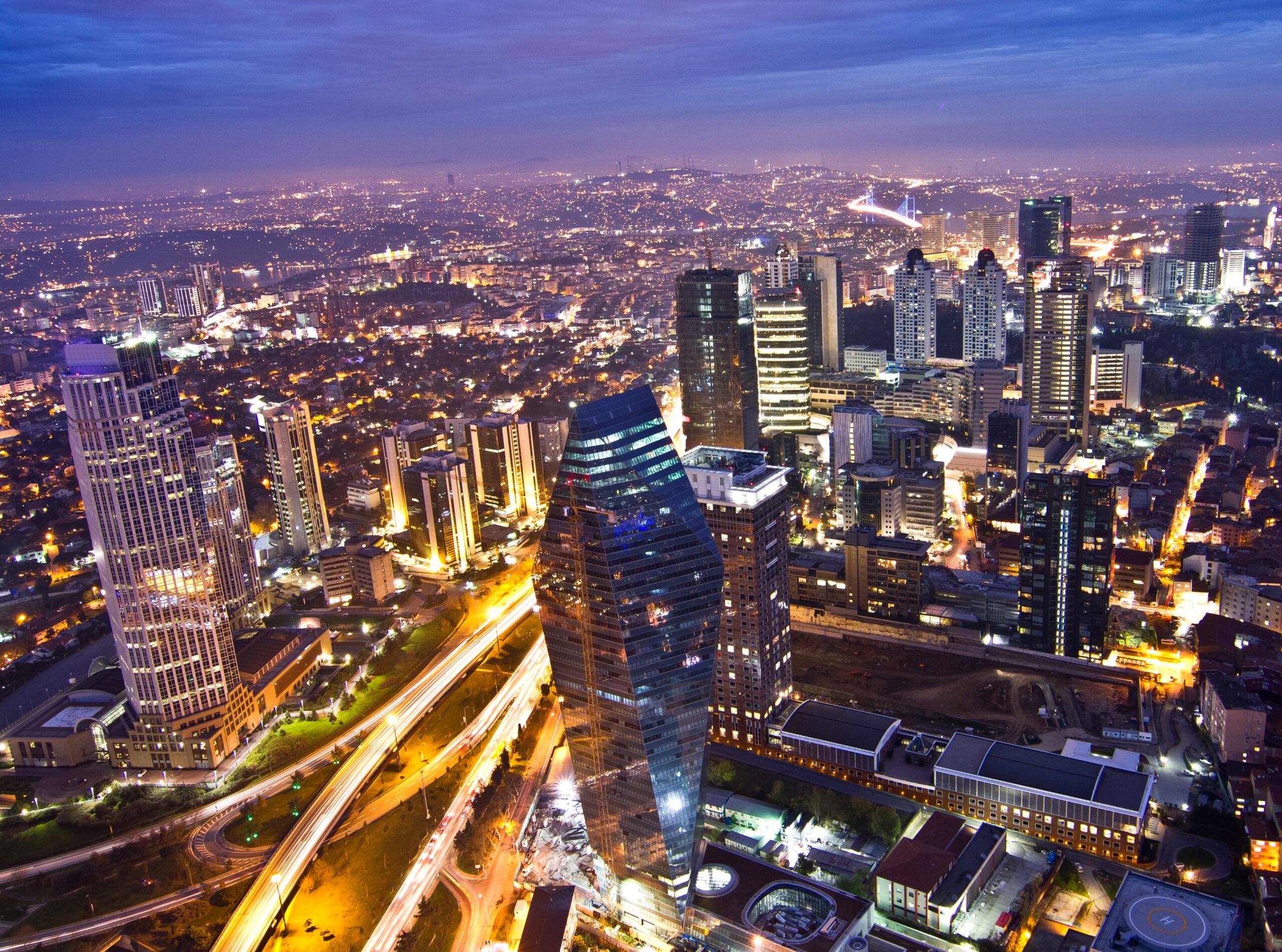 The business district in Istanbul with a setting sun and city lights visible.