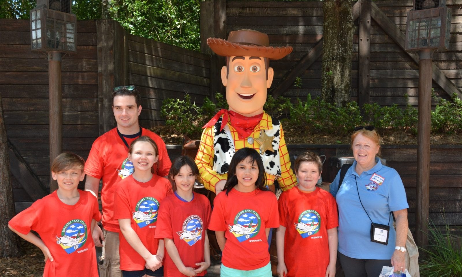 A photo of a gorup of children posing with the Walt Disney character Woody from Toy Story