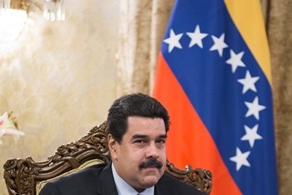 Nicolás Maduro seated in front of the Venezuelan flag during a government meeting, illustrating the Venezuela aviation ban, tightened Venezuela airspace controls, rising U.S.-Venezuela tensions, Venezuela airline restrictions 2025, and aviation used as political leverage.