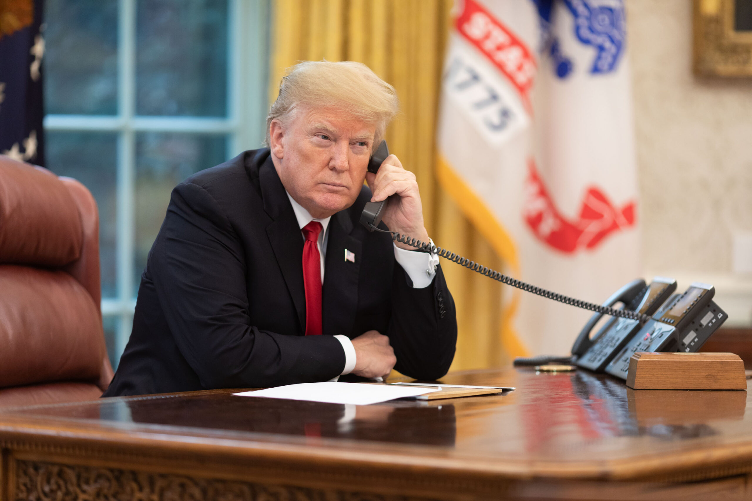 Donald Trump on a phone call in the Oval Office. U.S.-Venezuela tensions linked to the Venezuela aviation ban, tighter Venezuela airspace, Venezuela airline restrictions 2025, and aviation used as political leverage.