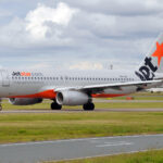 An orange and silver Jetstar plane comes in for landing.