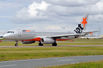 An orange and silver Jetstar plane comes in for landing.
