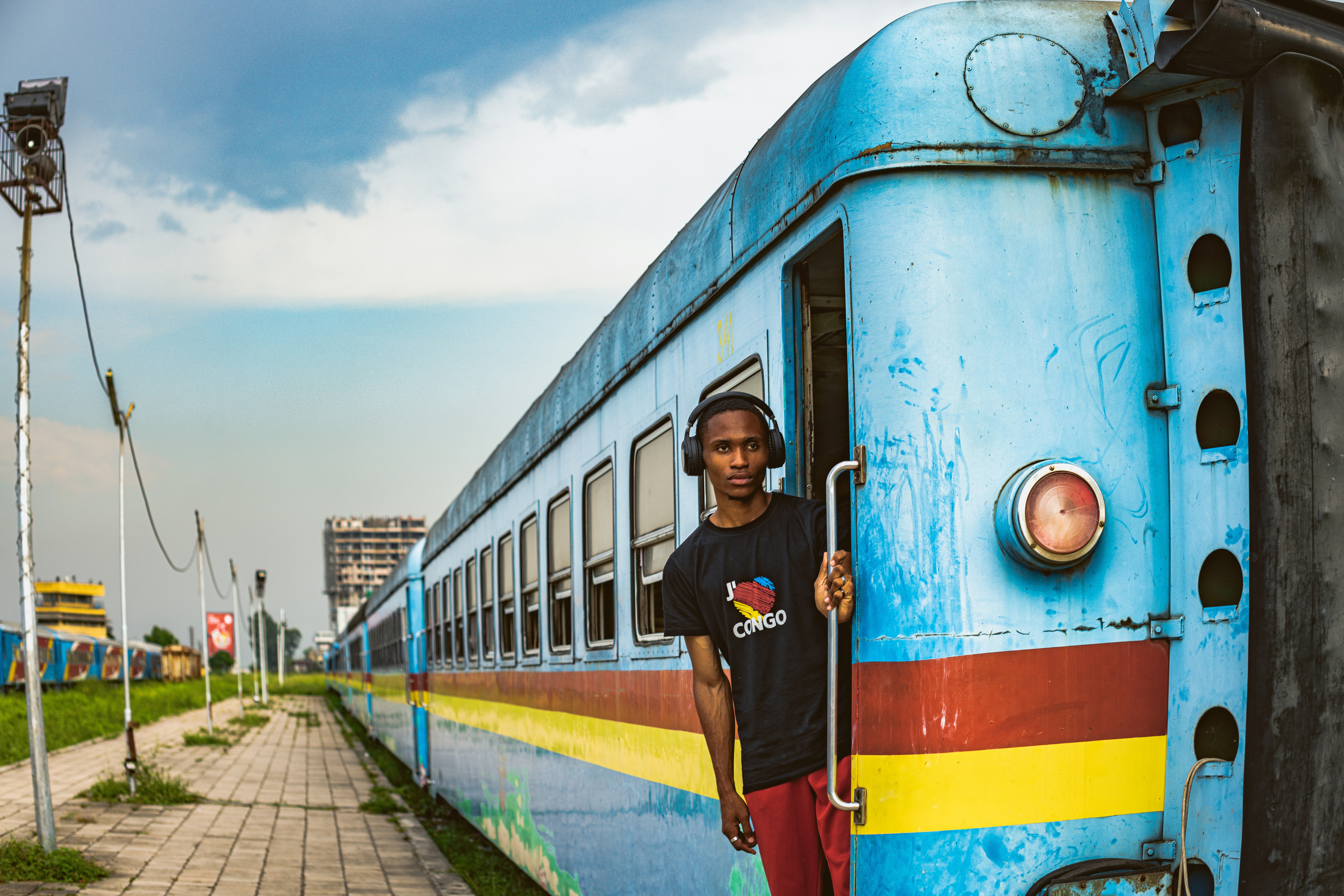 A man in a Congo shirt on the side of a blue train 