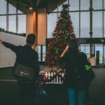 A couple standing in front of a Christmas tree at the airport