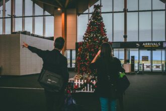 A couple standing in front of a Christmas tree at the airport