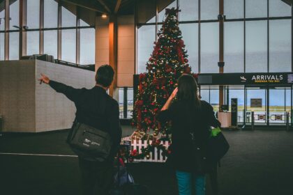 A couple standing in front of a Christmas tree at the airport