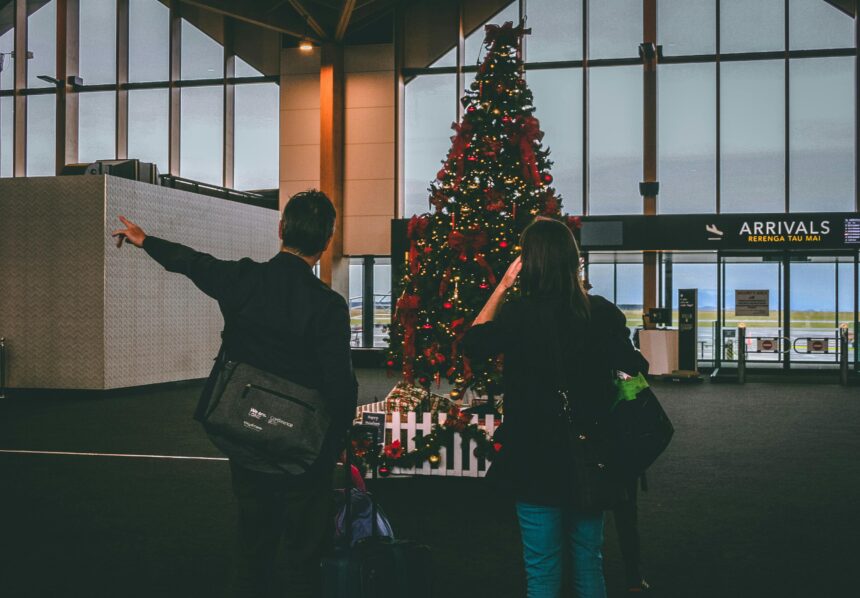A couple standing in front of a Christmas tree at the airport