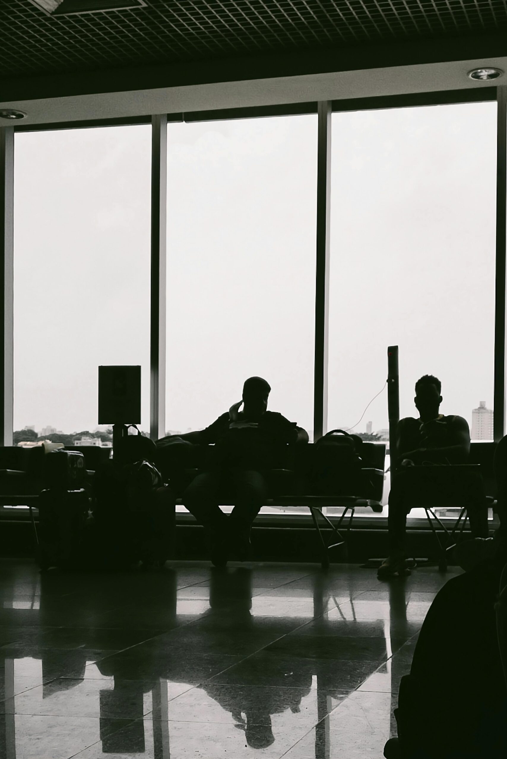 People Sitting and Waiting in Shadow at Airport