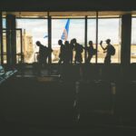 Group of People Walking Near Clear Glass Window With a View of White Airplane Parked during Daytime