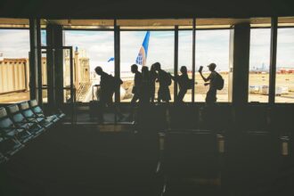 Group of People Walking Near Clear Glass Window With a View of White Airplane Parked during Daytime