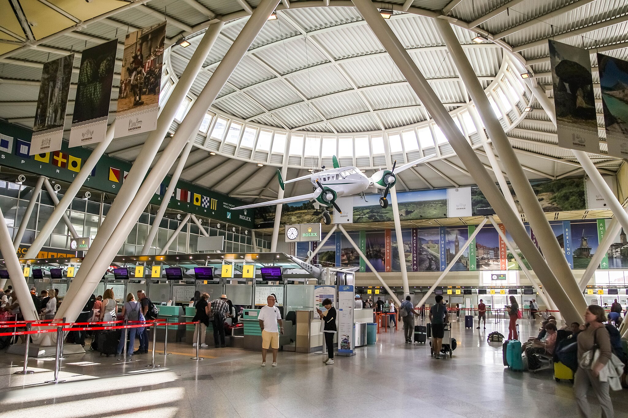 The check-in counters at Olbia airport in Sardinia. The architecture is unique with a rounded skylight making the lobby bright.