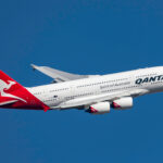 An Airbus A380 flying against a clear blue sky.