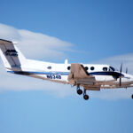 A twin-engine turboprop aircraft serving as a Civilian Air Ambulance for St Luke's flies in the blue sky.