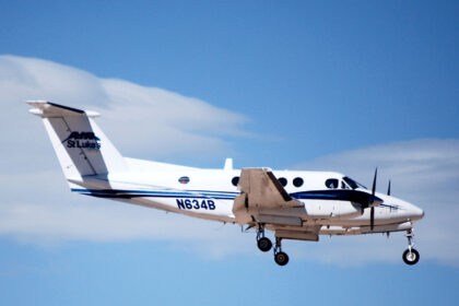 A twin-engine turboprop aircraft serving as a Civilian Air Ambulance for St Luke's flies in the blue sky.