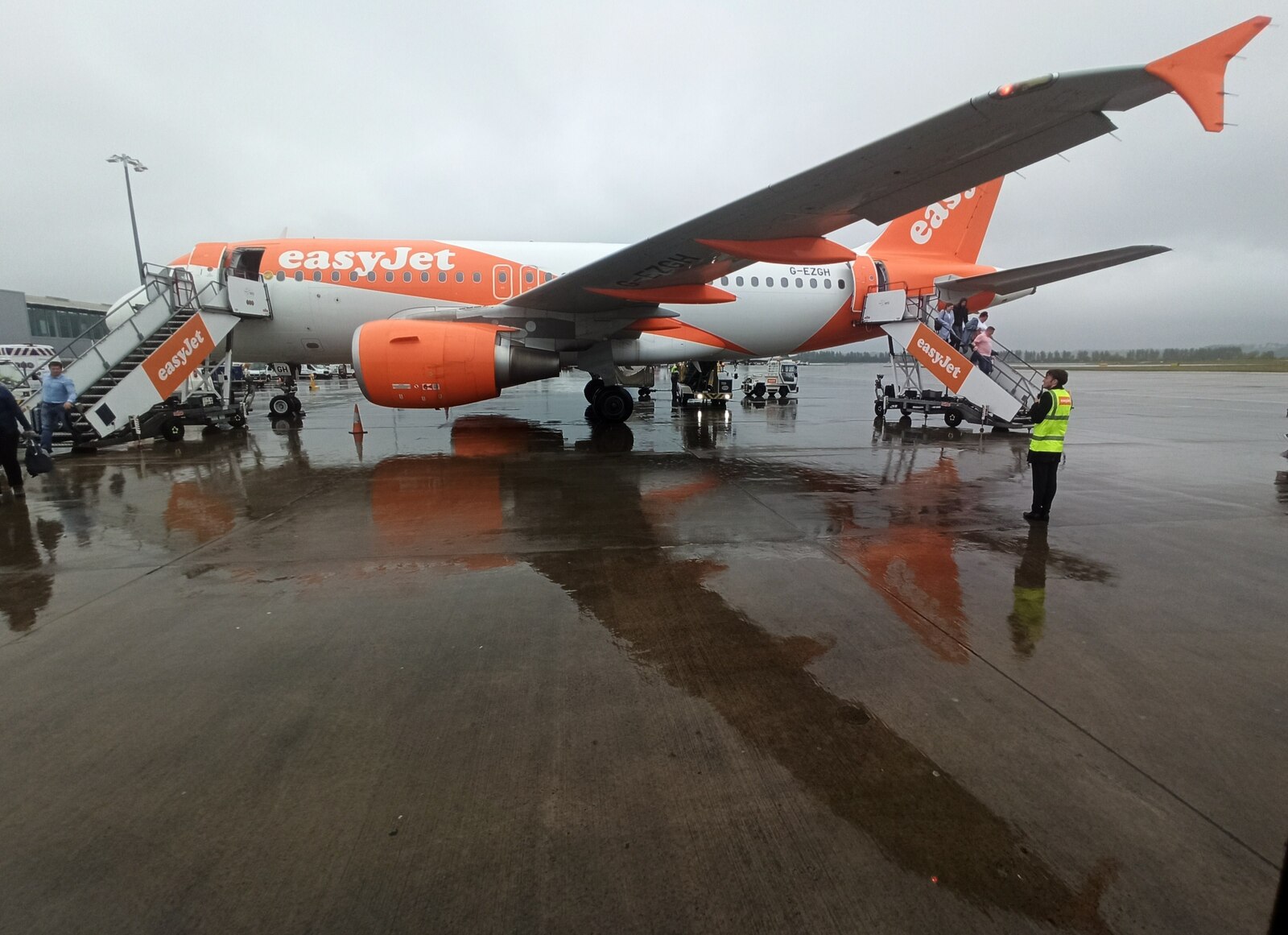 An easyJet plane boarding passengers on a rainy runway.