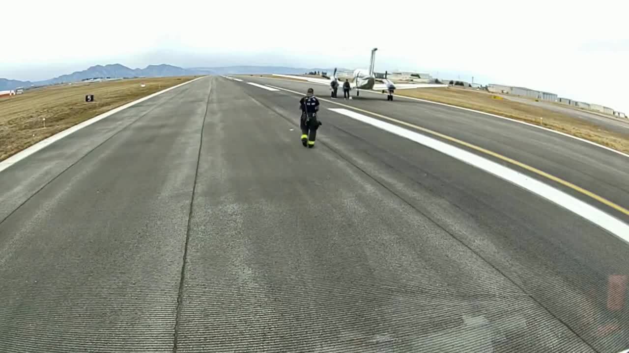 The small Beechcraft Super King Air 200 is on the runway, being approached by emergency personnel.