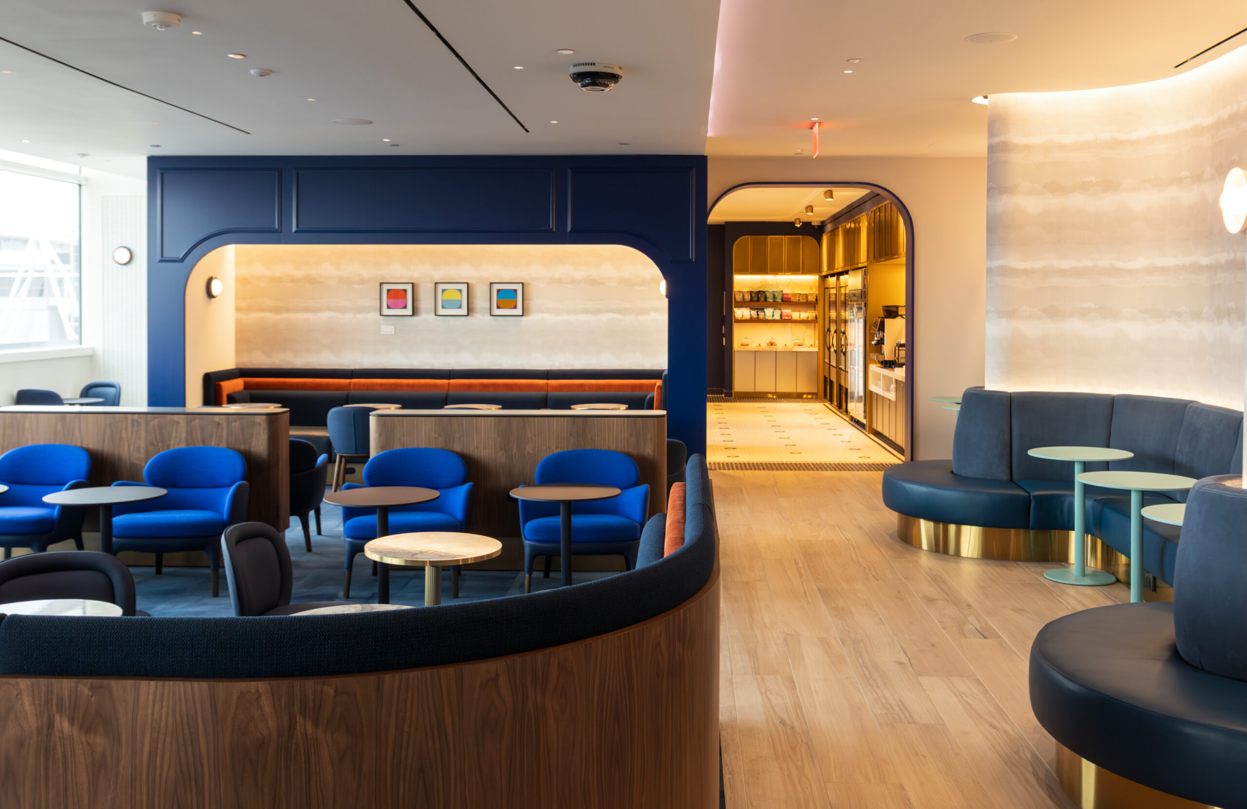 The second floor of BlueHouse. Different chairs in bright and navy blue are dotted around a room divided by wooden panels. There is a corridor leading to a kitchen/buffet area.