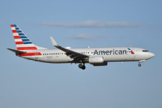 An American Airlines Boeing 737 flying in the sky with some clouds.