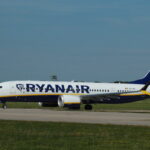 A Ryanair Boeing 737-8200 Max on the runway, surrounded by grass.