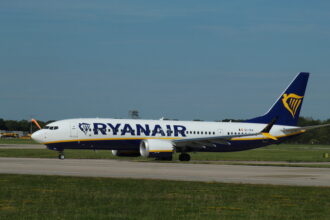 A Ryanair Boeing 737-8200 Max on the runway, surrounded by grass.