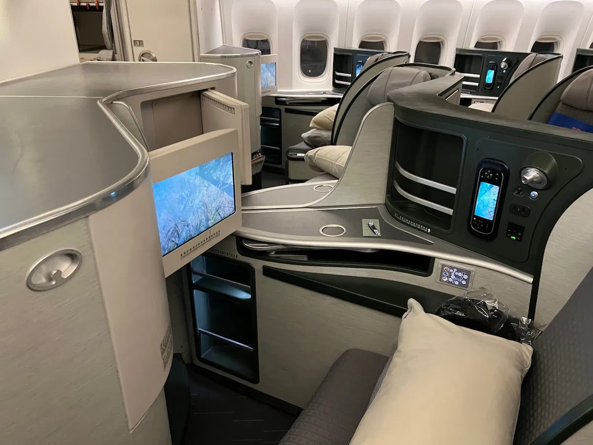 EVA Air's business cabin showing a seat, personal mini TV, and windows in the background among other amenities.
