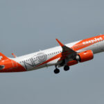 An easyJet Airbus A320neo flies in the grey sky.