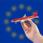Hand holding a miniature plane on national flag of European Union