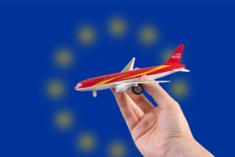 Hand holding a miniature plane on national flag of European Union
