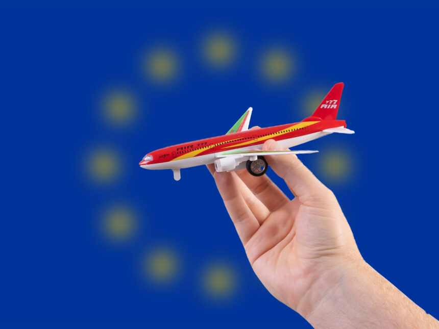 Hand holding a miniature plane on national flag of European Union