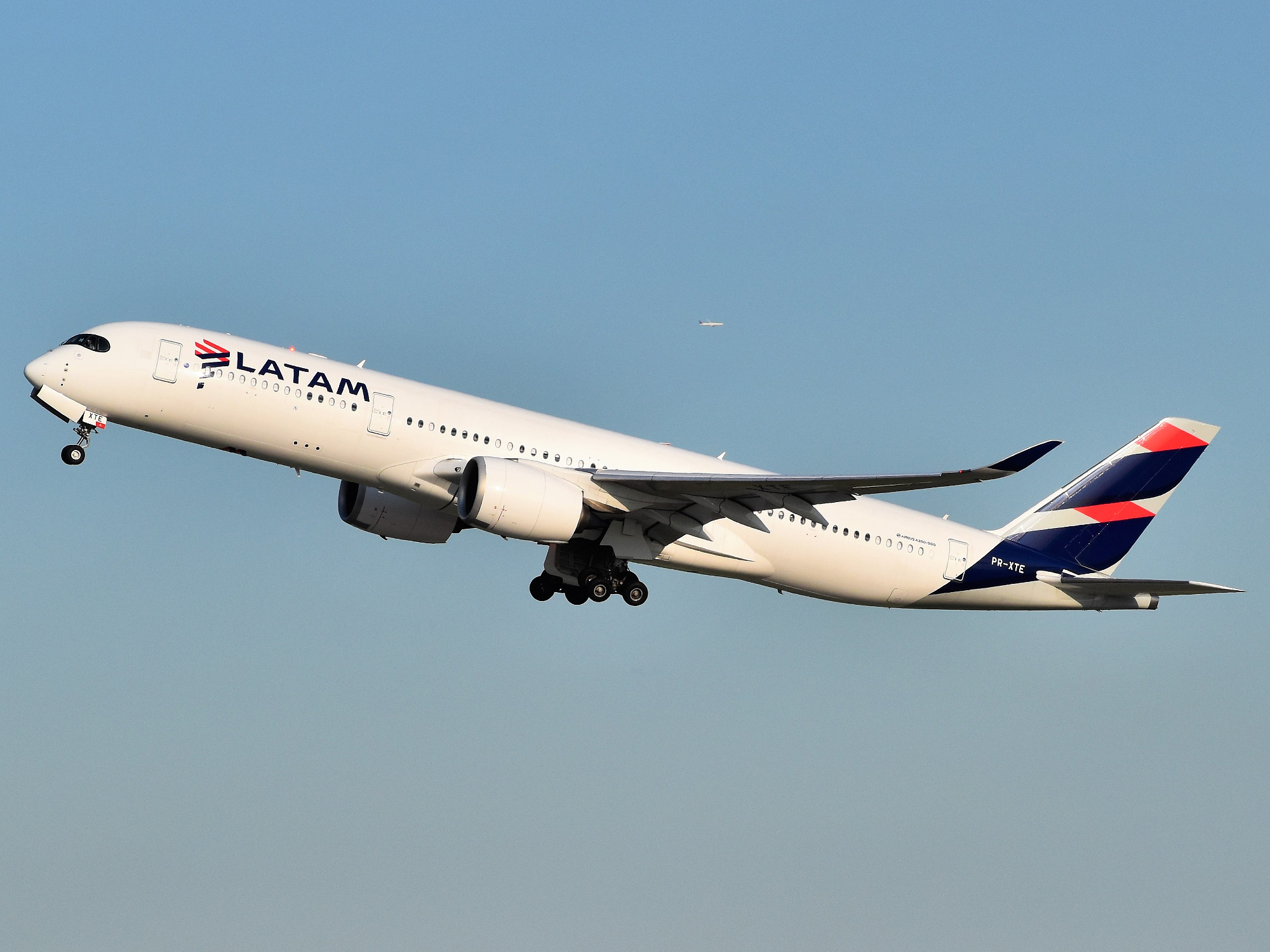 Image shows a LATAM aircraft taking off into the sky in daylight while the landing gear is out.