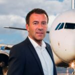 Picture of Scott Collier, CEO of ACS, standing in front of an airplane.