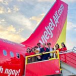 Vietjet Standing Vice President To Viet Thang, wearing a dark blue blazer, and flight crews pose in front of one of the airline’s new aircraft during a welcoming ceremony