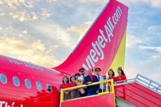 Vietjet Standing Vice President To Viet Thang, wearing a dark blue blazer, and flight crews pose in front of one of the airline’s new aircraft during a welcoming ceremony