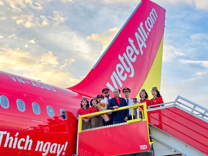 Vietjet Standing Vice President To Viet Thang, wearing a dark blue blazer, and flight crews pose in front of one of the airline’s new aircraft during a welcoming ceremony