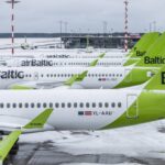 Tails of multiple Airbus A220 airBaltic aircraft lined up on a snow-covered tarmac