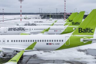 Tails of multiple Airbus A220 airBaltic aircraft lined up on a snow-covered tarmac