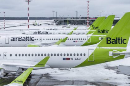 Tails of multiple Airbus A220 airBaltic aircraft lined up on a snow-covered tarmac