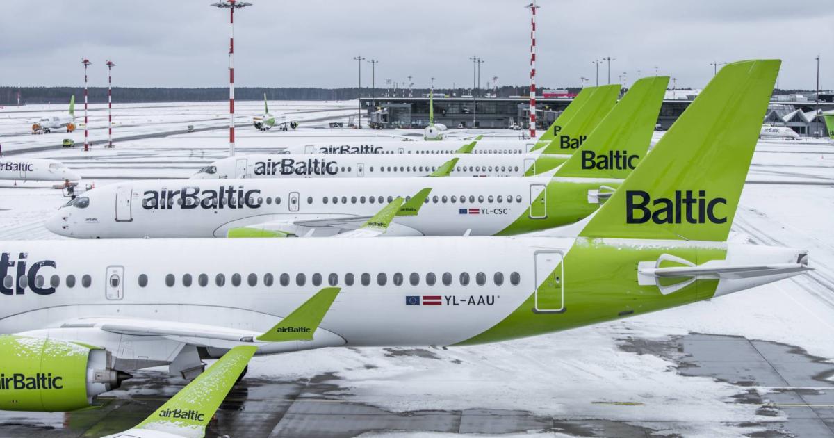 Tails of multiple Airbus A220 airBaltic aircraft lined up on a snow-covered tarmac