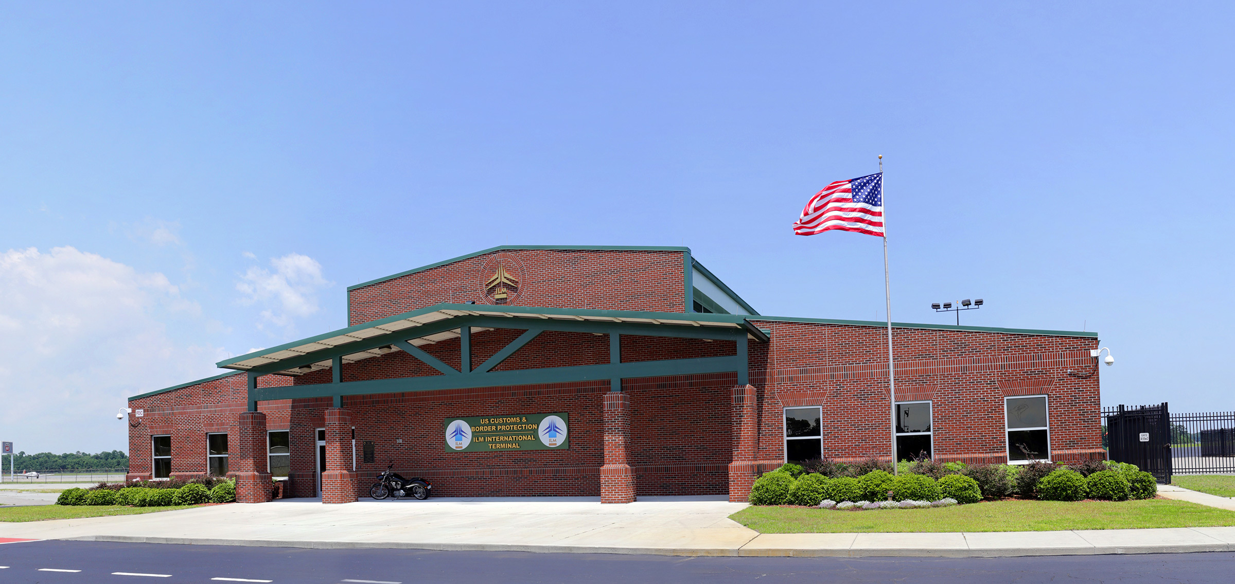 A sign on a brick building reads "US Customs and Border Protection" and "ILM International Terminal"