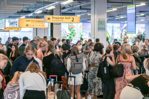 Passengers wait for their luggage at the arrivals baggage belt