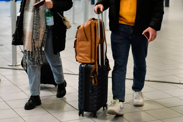 A photo of two people from the waist down carrying/pulling their luggage