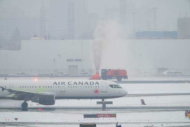 An Air Canada aircraft taxies as machinery blows snow in the background, during heavy snow at Toronto Pearson International Airport